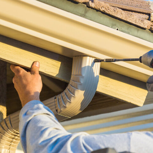 worker attaching gutters to fascia